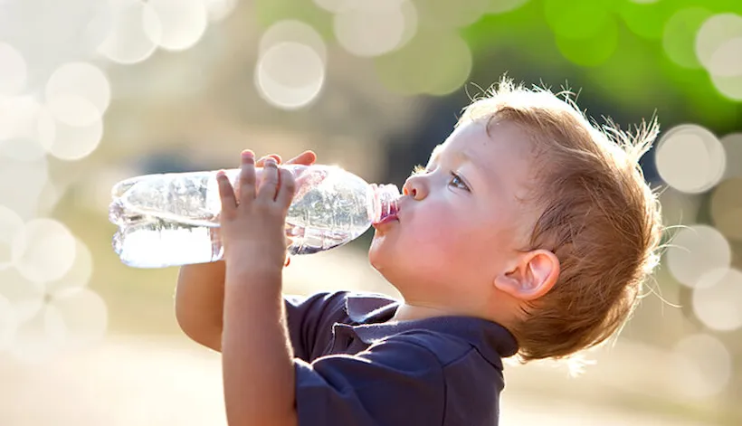 Little boy drinking water from a water bottle.